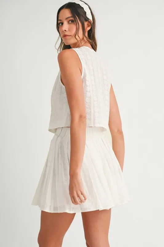 Two-piece set featuring an eyelet lace top and mini skirt, styled for a trendy and feminine look