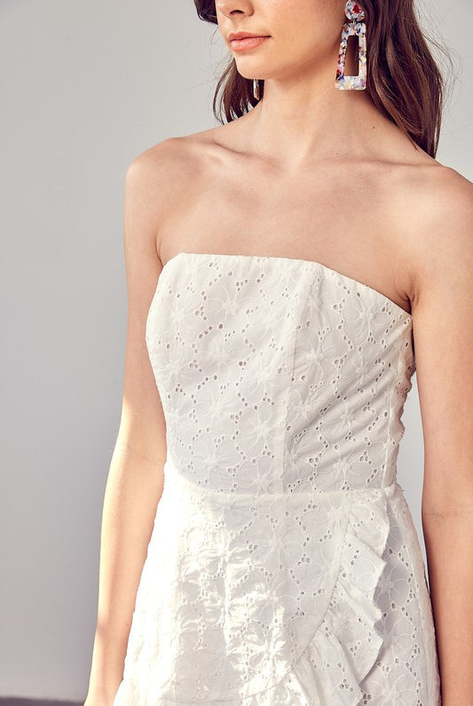 Model wearing The Maren Eyelet Romper featuring white eyelet fabric and ruffle details, STRAPLESS, perfect for spring and summer events