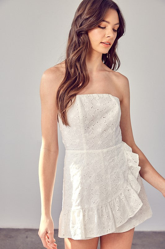 Model wearing The Maren Eyelet Romper featuring white eyelet fabric and ruffle details, STRAPLESS, perfect for spring and summer events