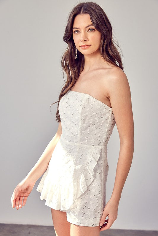 Model wearing The Maren Eyelet Romper featuring white eyelet fabric and ruffle details, STRAPLESS, perfect for spring and summer events