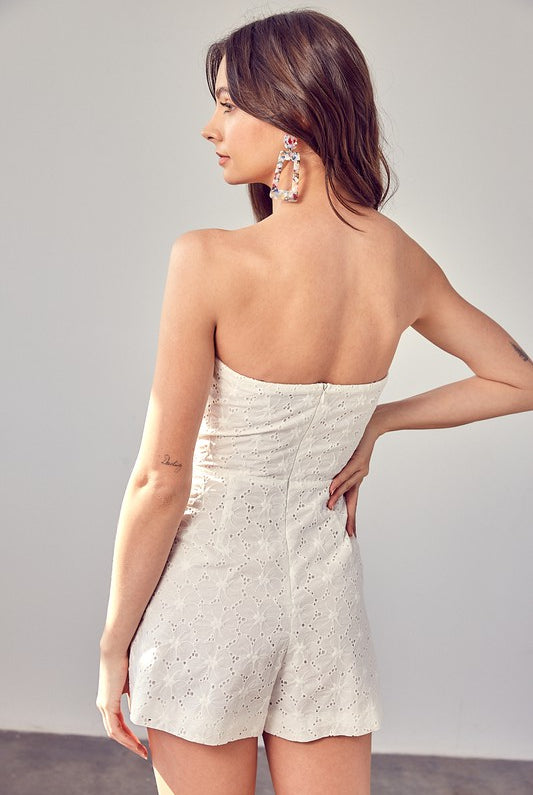 Model wearing The Maren Eyelet Romper featuring white eyelet fabric and ruffle details, STRAPLESS, perfect for spring and summer events