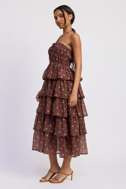 Woman wearing a brown tiered dress with light blue polka dots side view