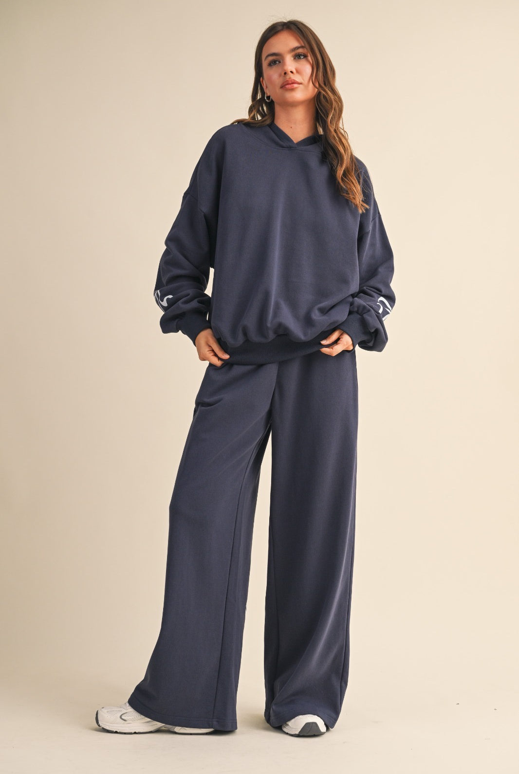 Model wearing navy wide-leg sweatpants with light blue bow details, styled with a matching navy hoodie.