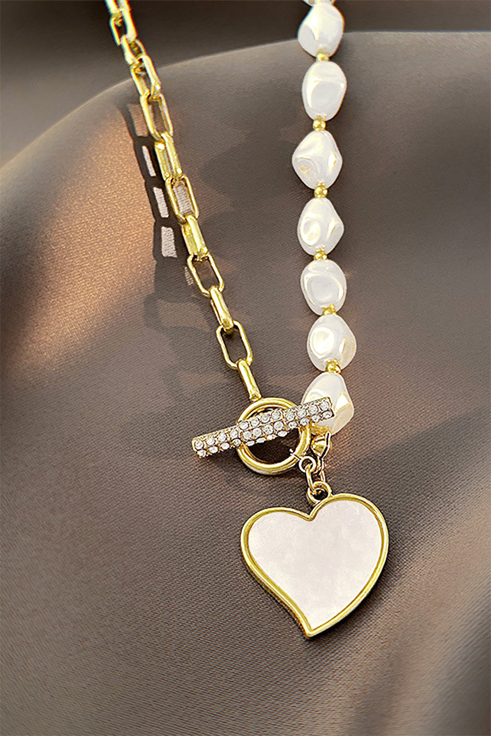 Necklace with heart pendant and beaded chain on a brown surface