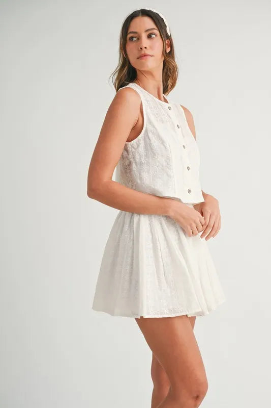 Two-piece set featuring an eyelet lace top and mini skirt, styled for a trendy and feminine look