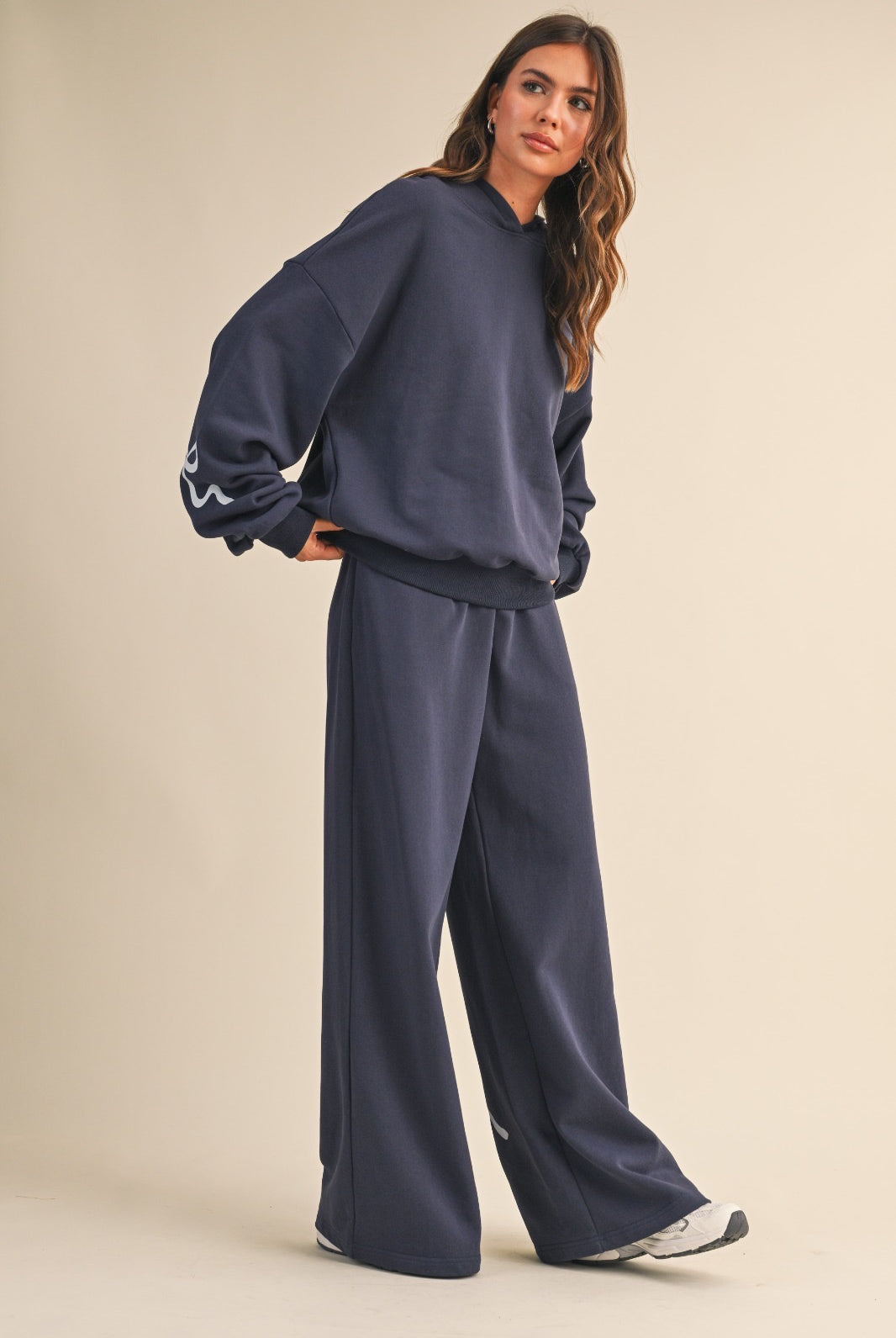 Model wearing navy wide-leg sweatpants with light blue bow details, styled with a matching navy hoodie.