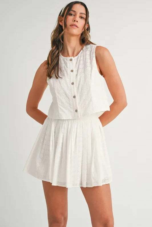 Two-piece set featuring an eyelet lace top and mini skirt, styled for a trendy and feminine look