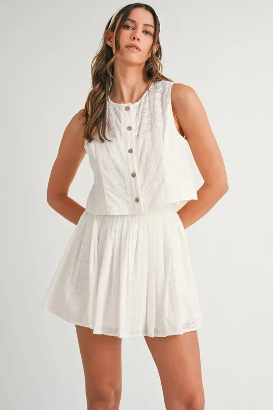 Two-piece set featuring an eyelet lace top and mini skirt, styled for a trendy and feminine look