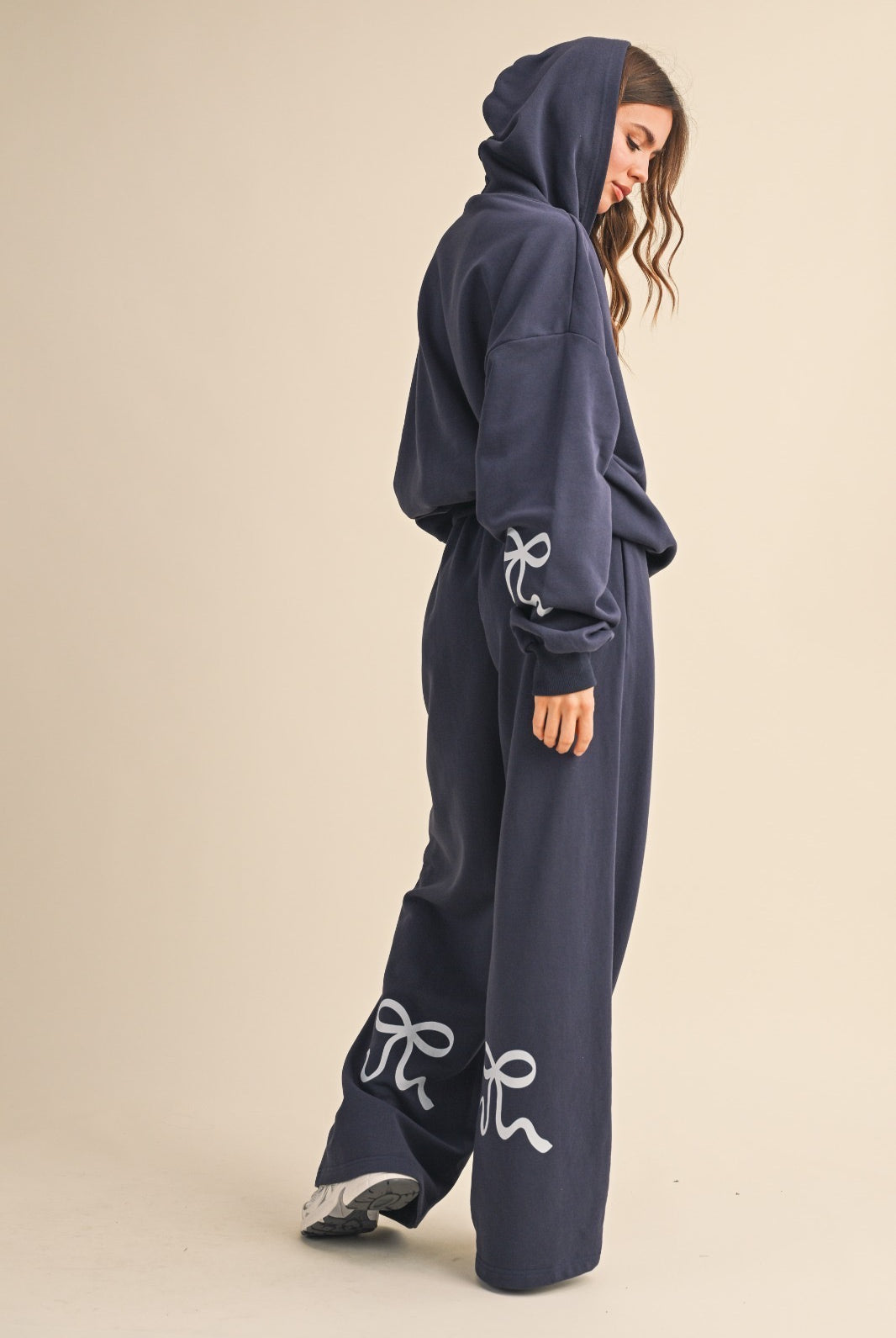 Model wearing navy wide-leg sweatpants with light blue bow details, styled with a matching navy hoodie.
