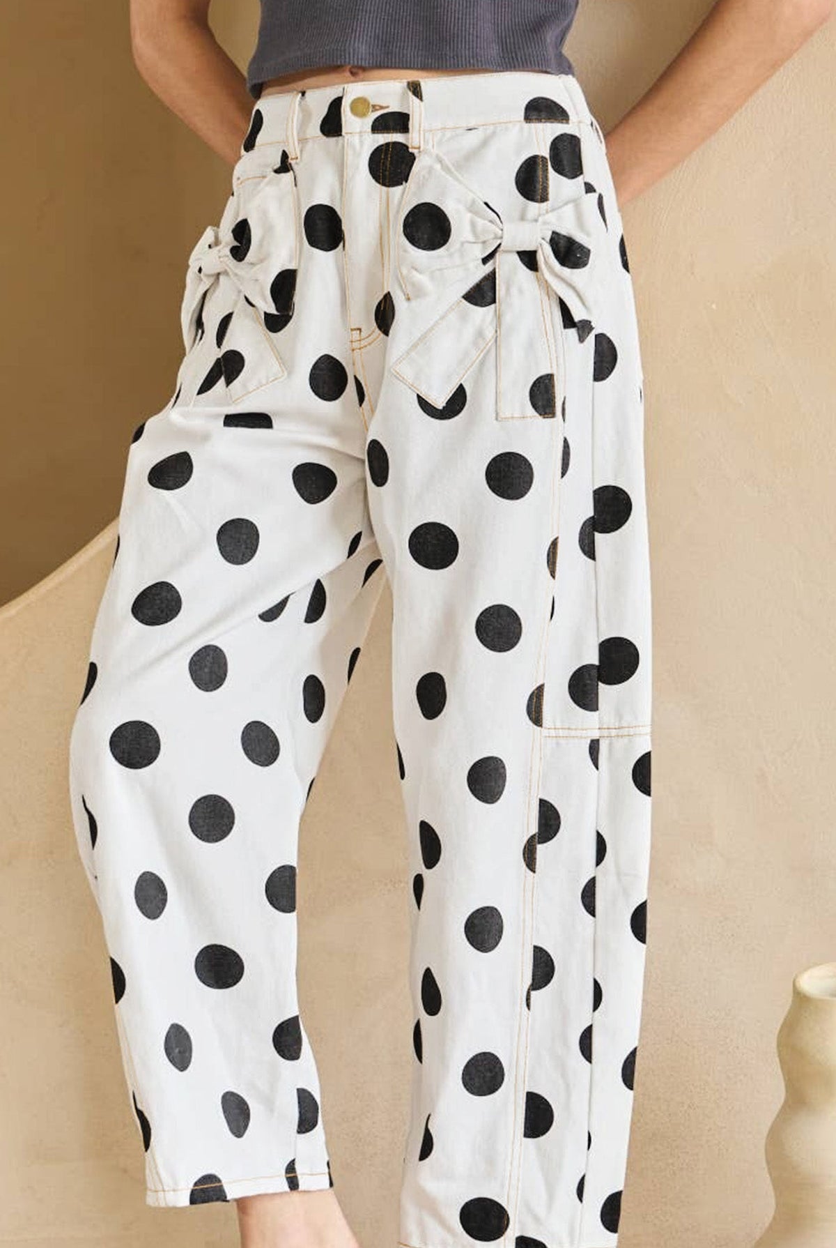 Person wearing white pants with black polka dots in a minimal indoor setting.