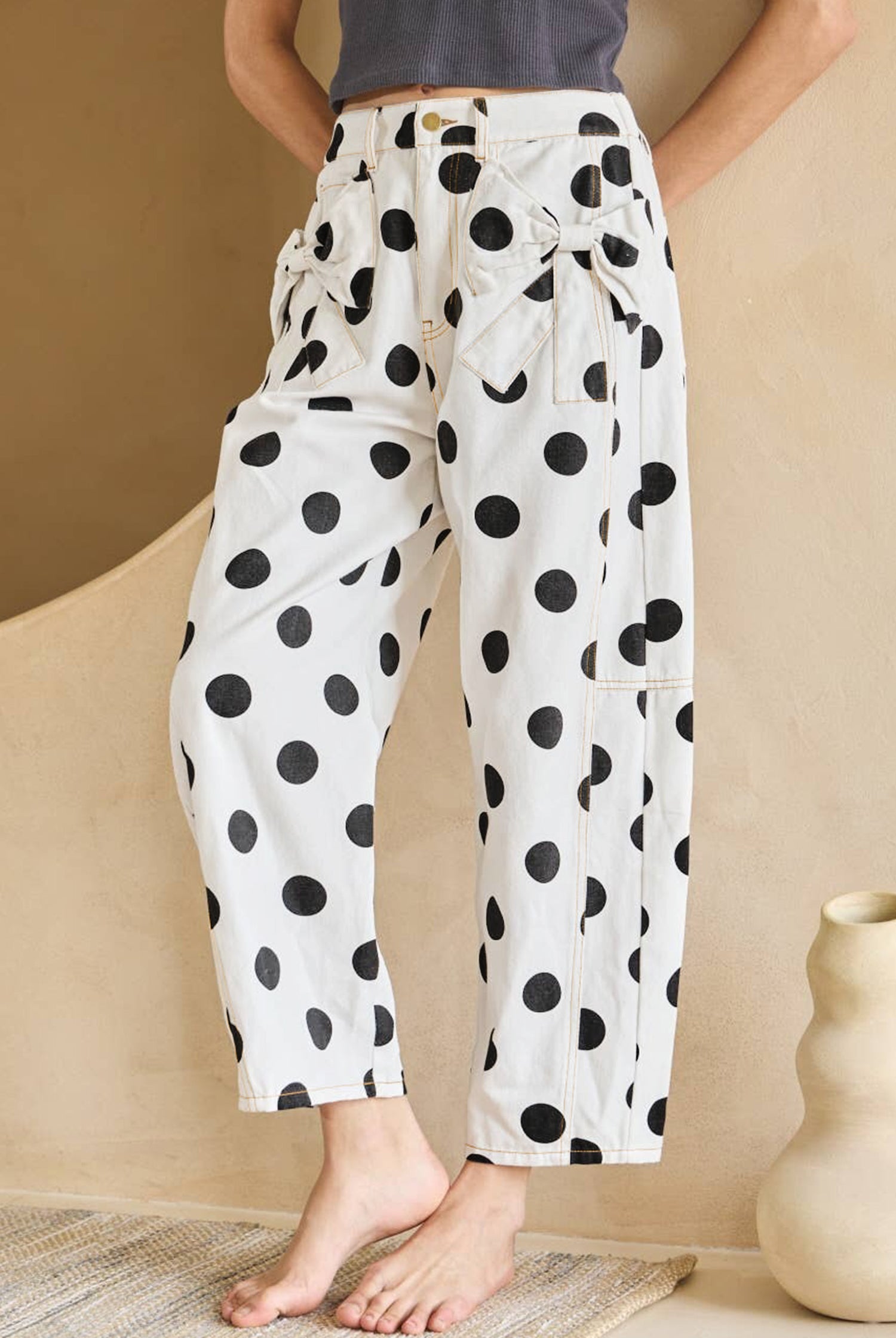 Person wearing white pants with black polka dots in a minimal indoor setting.
