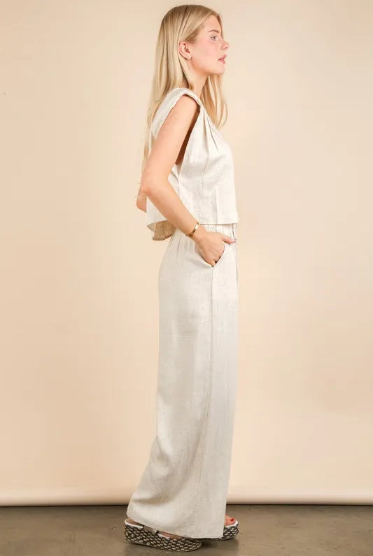 woman wearing a beige woven two-piece set with wide-leg pants and a sleeveless cropped top, styled for a chic minimalist look
