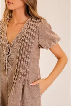 Casual washed utility romper featuring a deep V neck, adjustable-looking front tie detail, short sleeves, and relaxed shorts from Thread Bar Boutique