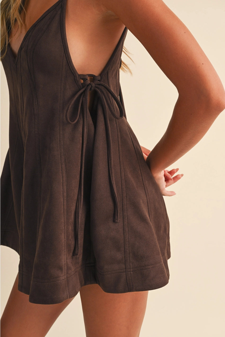 Close up Chocolate Brown Flare Chocolate brown textured flare romper with V-neckline, spaghetti straps, tie-side waist, and short flared hem