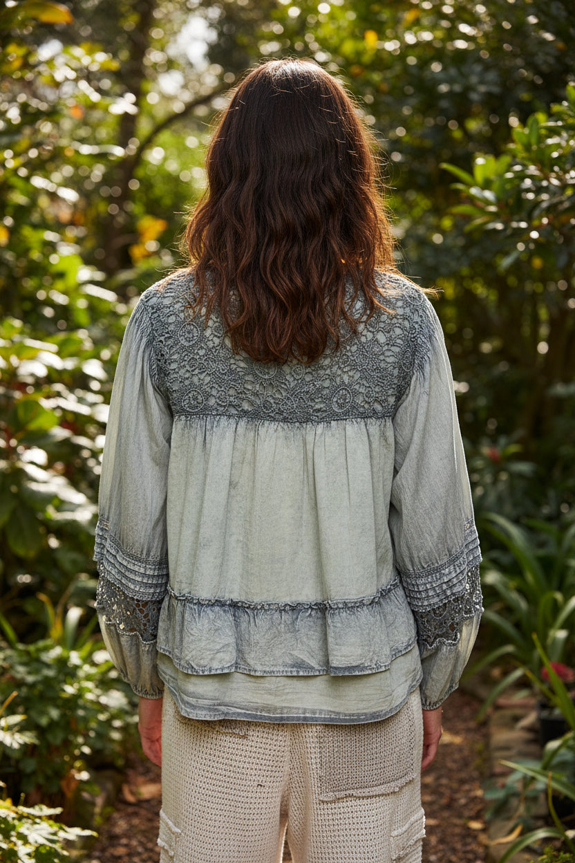cottagecore blouse featuring lace yoke details, pintuck pleats, long sleeves, tiered hemline, and breathable cotton fabric. Romantic feminine top ideal for jeans, brunch outfits, country concert looks, and trending cottagecore fashion.