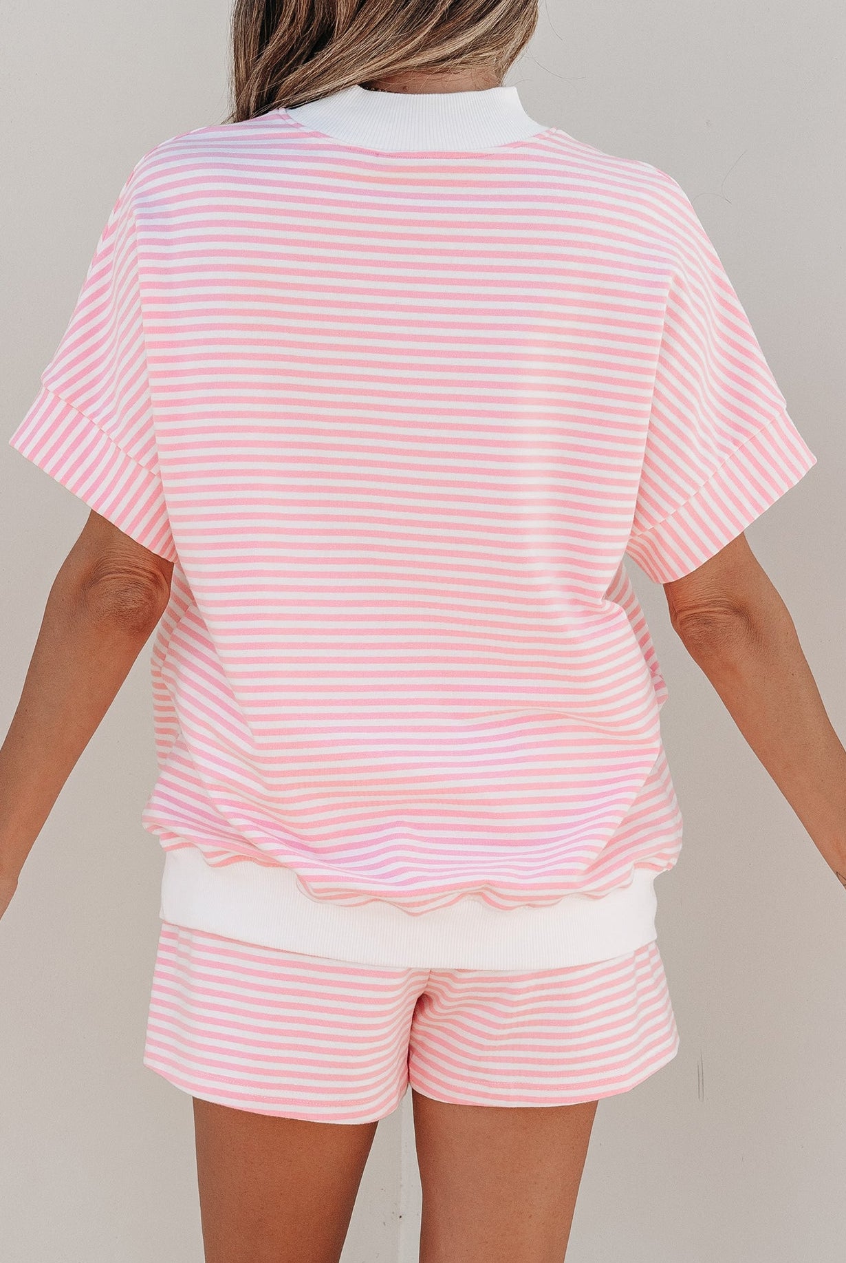 Person wearing a pink and white striped outfit with a plain background