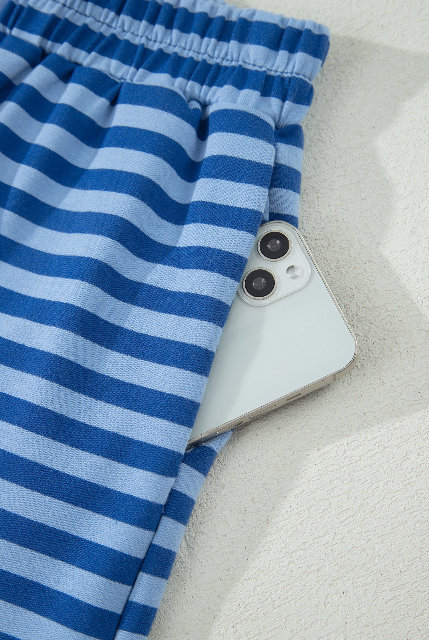 Blue striped fabric partially covering a smartphone on a light background
