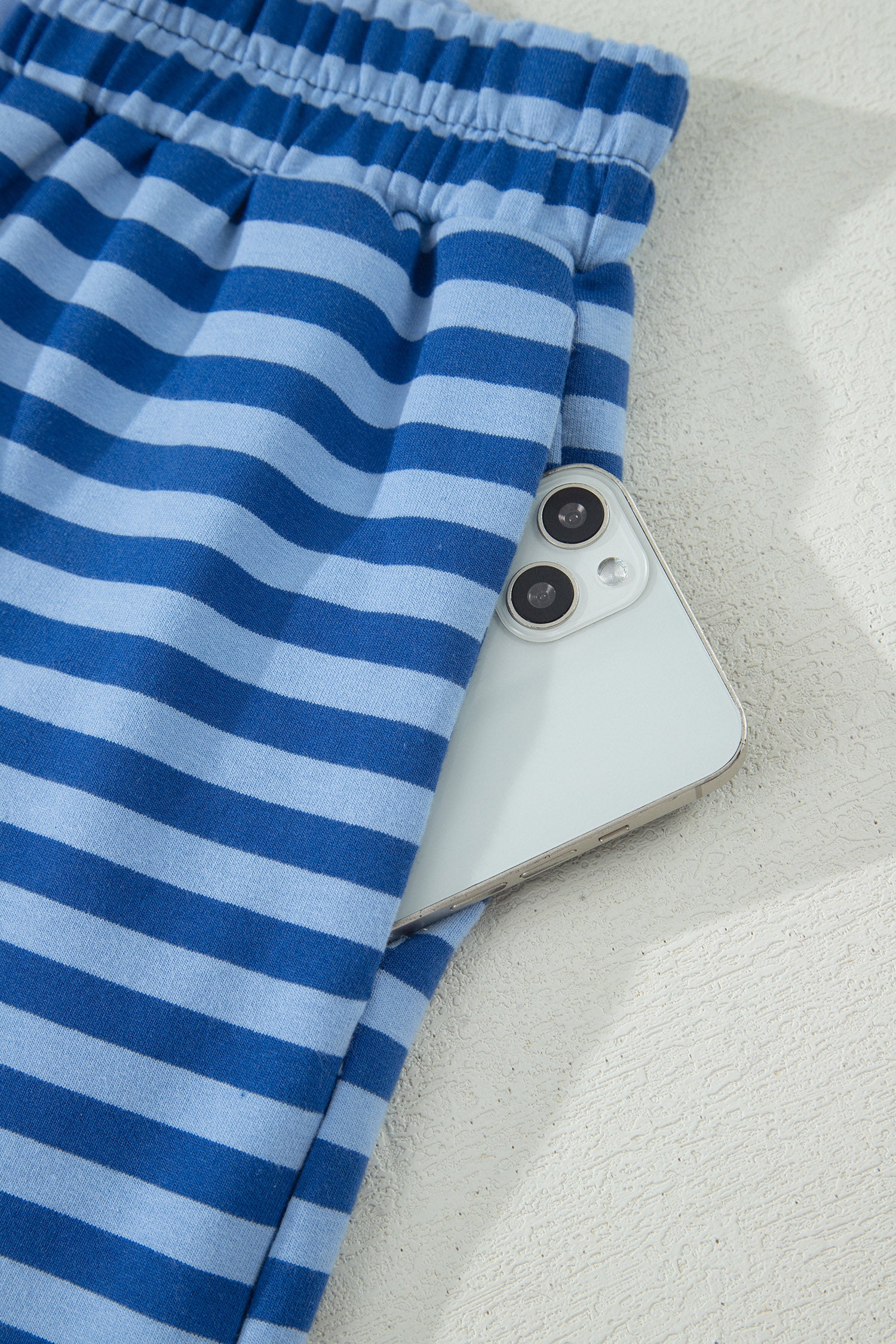 Blue striped fabric partially covering a smartphone on a light background