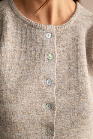 Detailed view of a soft women's knit sweater featuring textured fabric, subtle stretch, structured puff sleeves, crew neck, and button-down front for elevated casual style.
