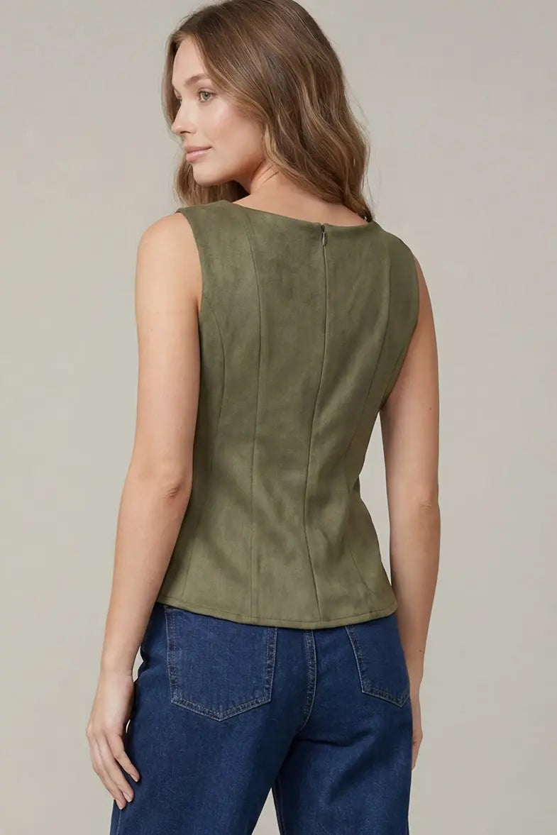 Women's sleeveless suede peplum blouse styled with tailored trousers for a polished office and business casual outfit