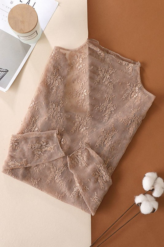 Folded beige lace garment on a brown surface with a white fluffy object and magazine in the background.