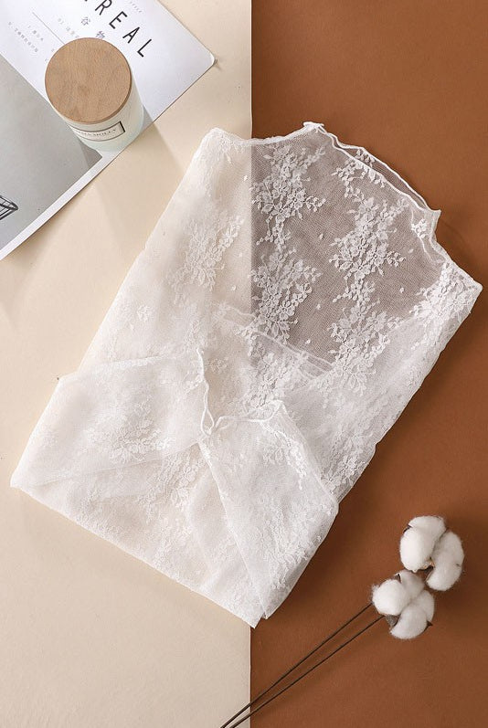 White lace fabric on a split beige and brown background with a cotton plant.