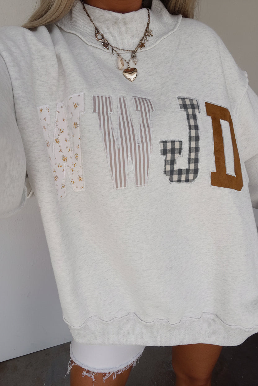 Women's WWJD embroidered patch sweatshirt with mixed floral, plaid, and striped fabric appliqué details, mock neck, long sleeves, and relaxed fit — a cozy Christian faith sweatshirt for everyday wear.