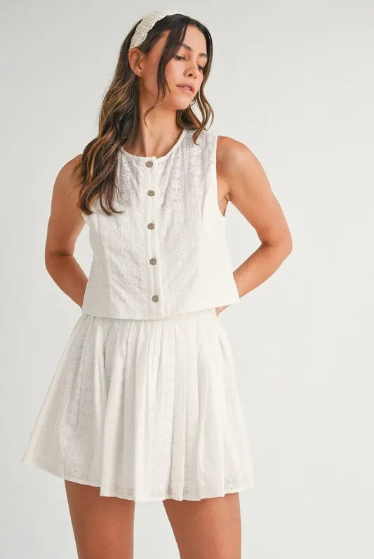 Two-piece set featuring an eyelet lace top and mini skirt, styled for a trendy and feminine look