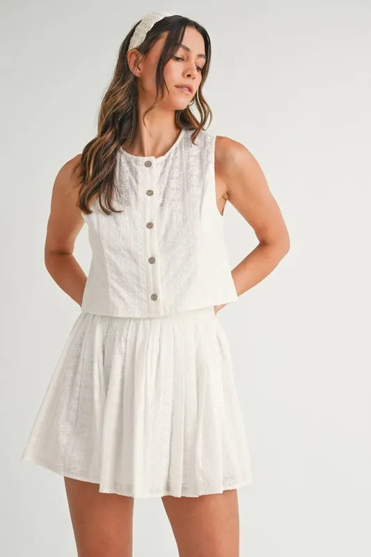 Two-piece set featuring an eyelet lace top and mini skirt, styled for a trendy and feminine look