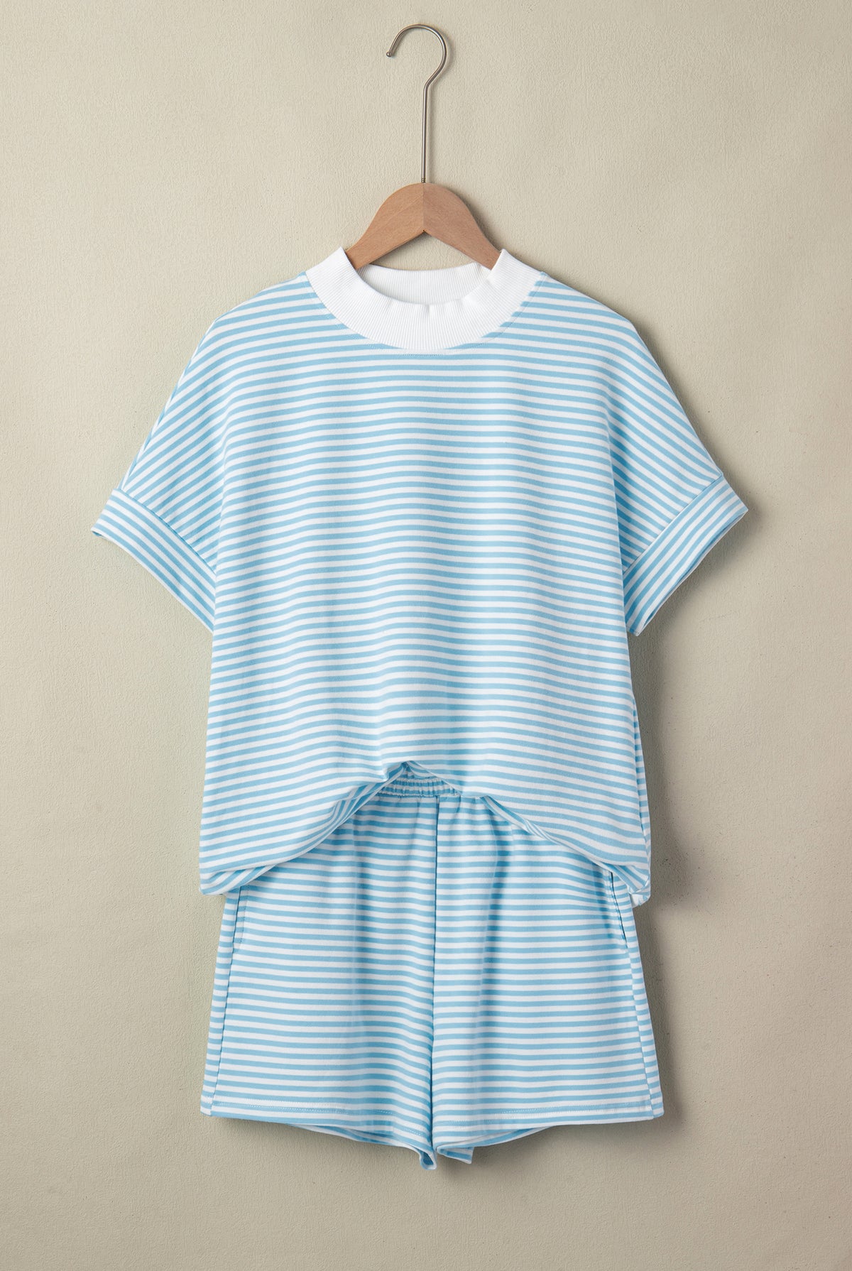 Blue and white striped outfit on a hanger against a beige background