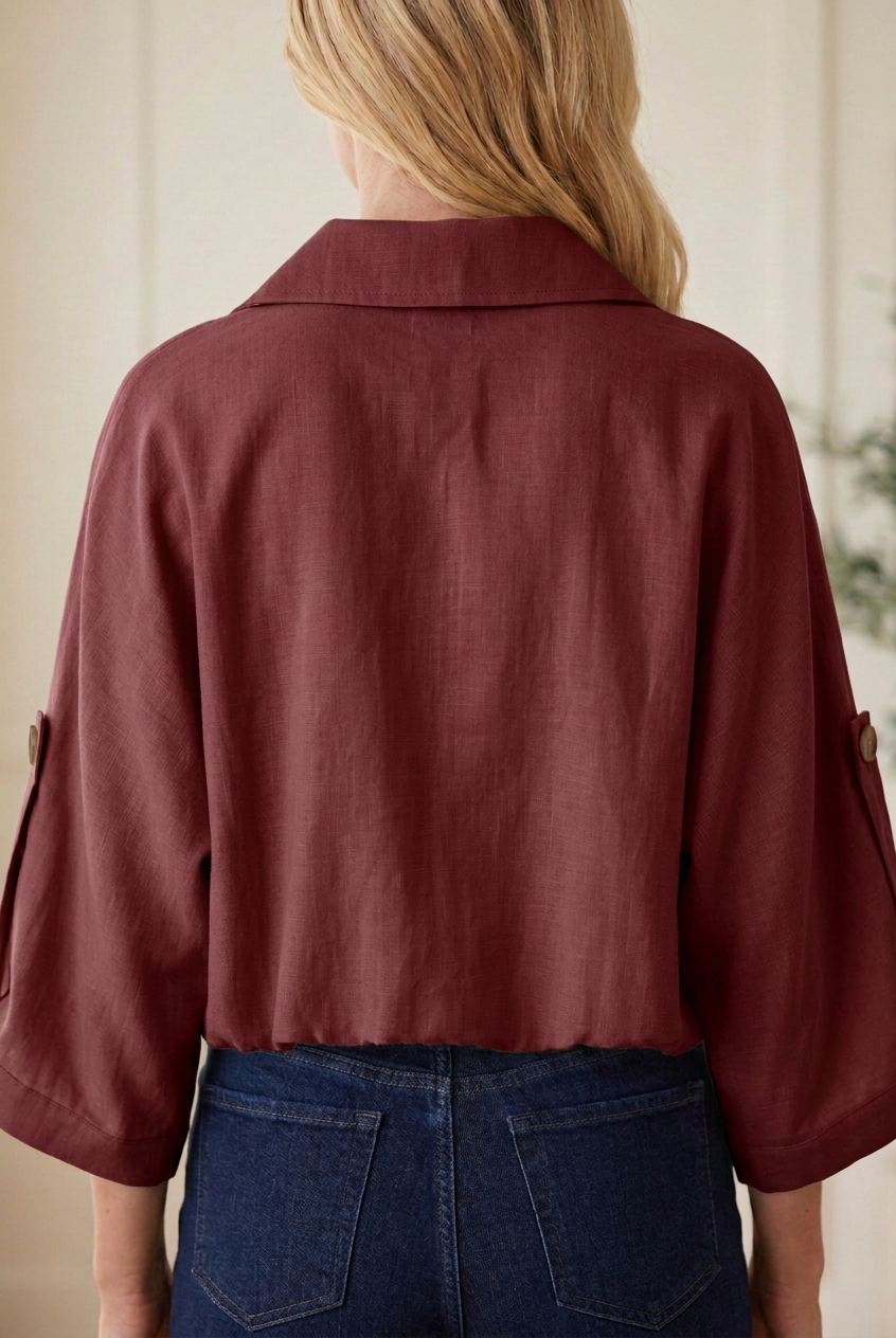 Back detail of taupe utility jacket showing folded collar, woven fabric, button-tab sleeves and gathered elastic hem