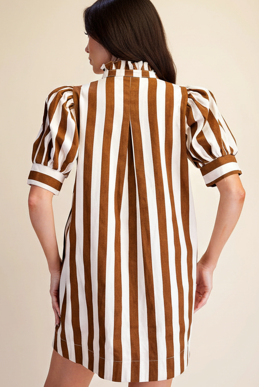 A woman shown from the back wearing a brown and white vertically striped dress with puff sleeves and a ruffled high neck, against a plain beige studio background.
