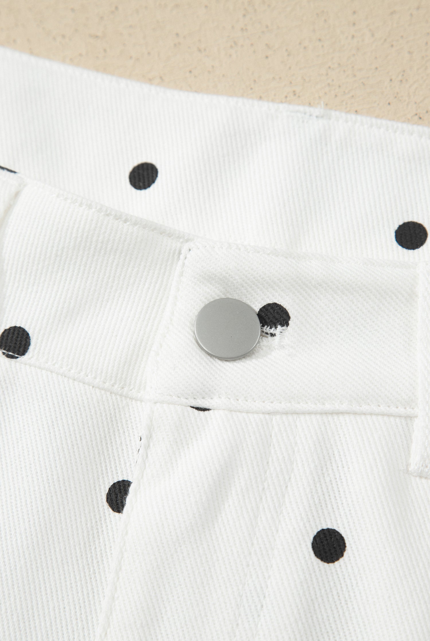 White fabric with black polka dots and a metal button