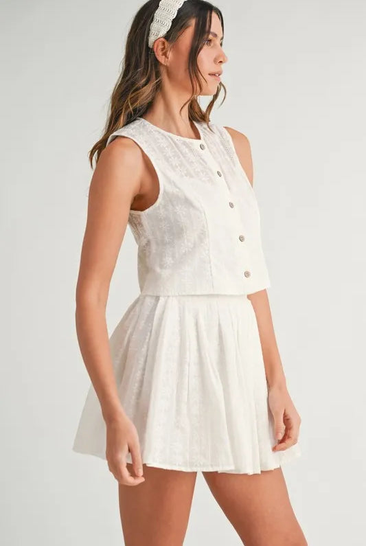 Two-piece set featuring an eyelet lace top and mini skirt, styled for a trendy and feminine look