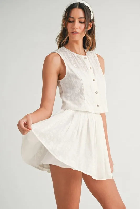 Two-piece set featuring an eyelet lace top and mini skirt, styled for a trendy and feminine look