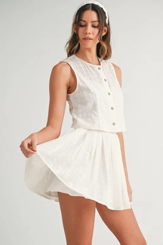 Two-piece set featuring an eyelet lace top and mini skirt, styled for a trendy and feminine look