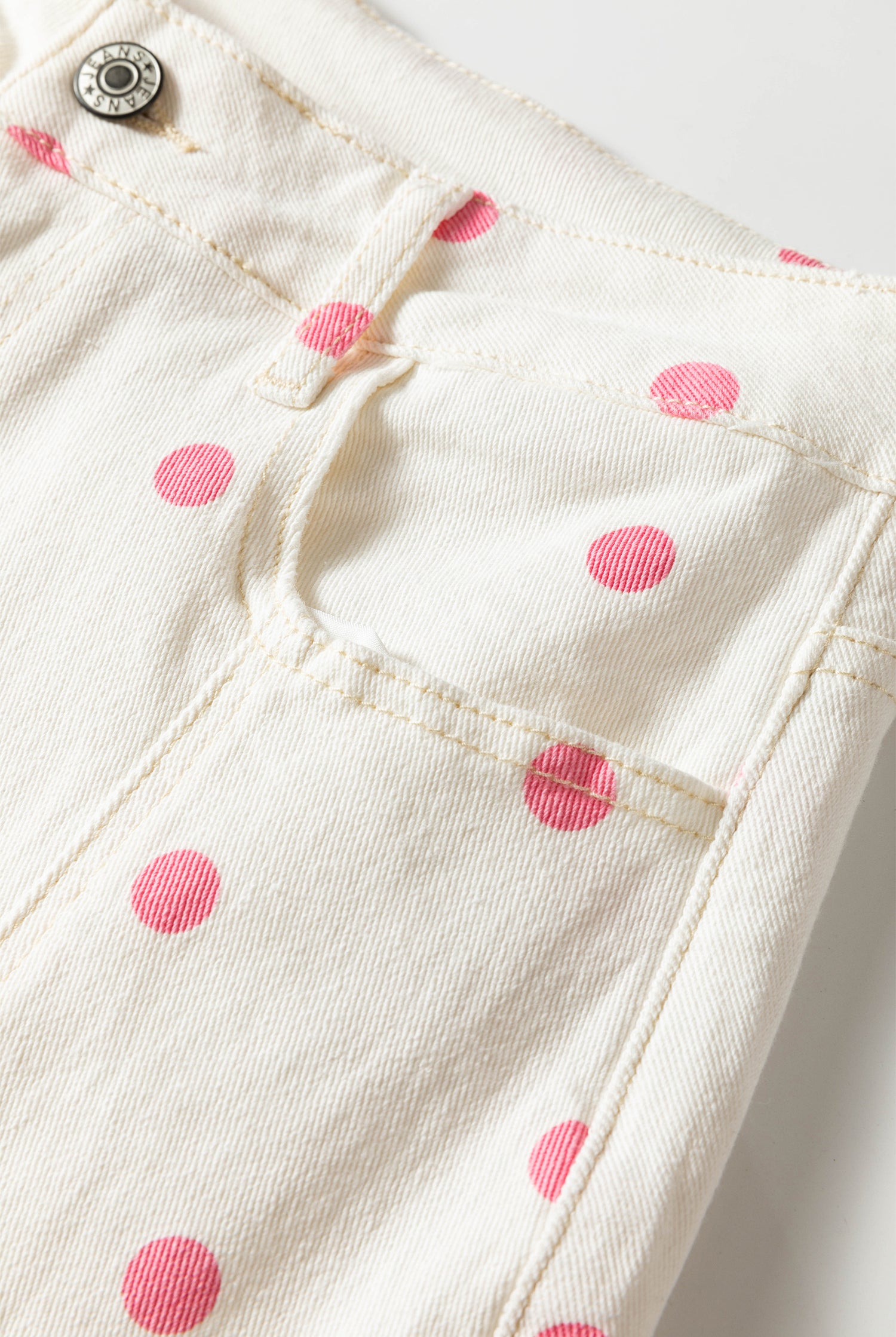 Close-up of white fabric with pink polka dots on a white background