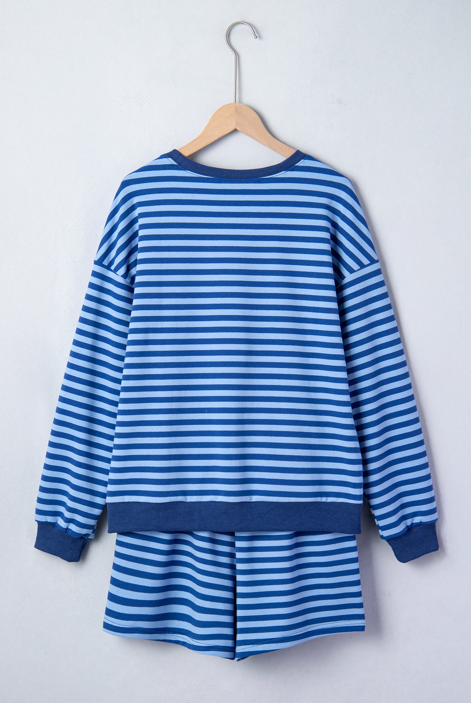 Blue and white striped dress on a wooden hanger against a white background
