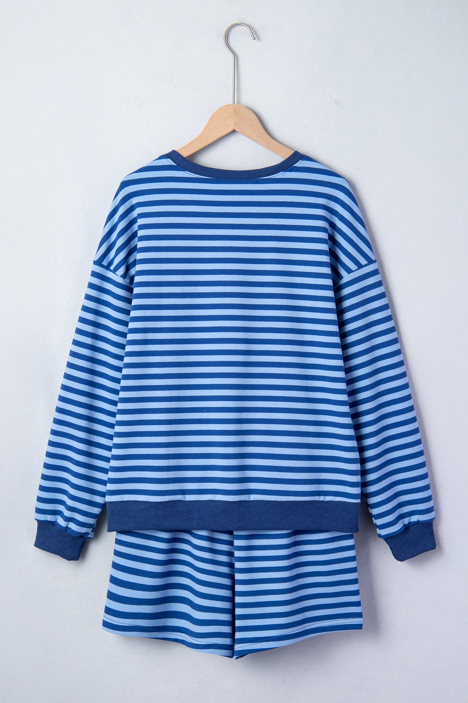 Blue and white striped dress on a wooden hanger against a white background