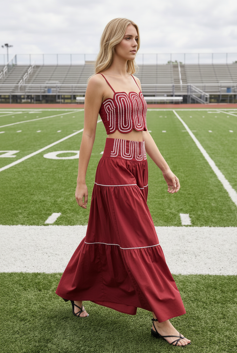 Blonde model wearing crimson red lace trim crop top and tiered maxi skirt set - side profile walking on football field