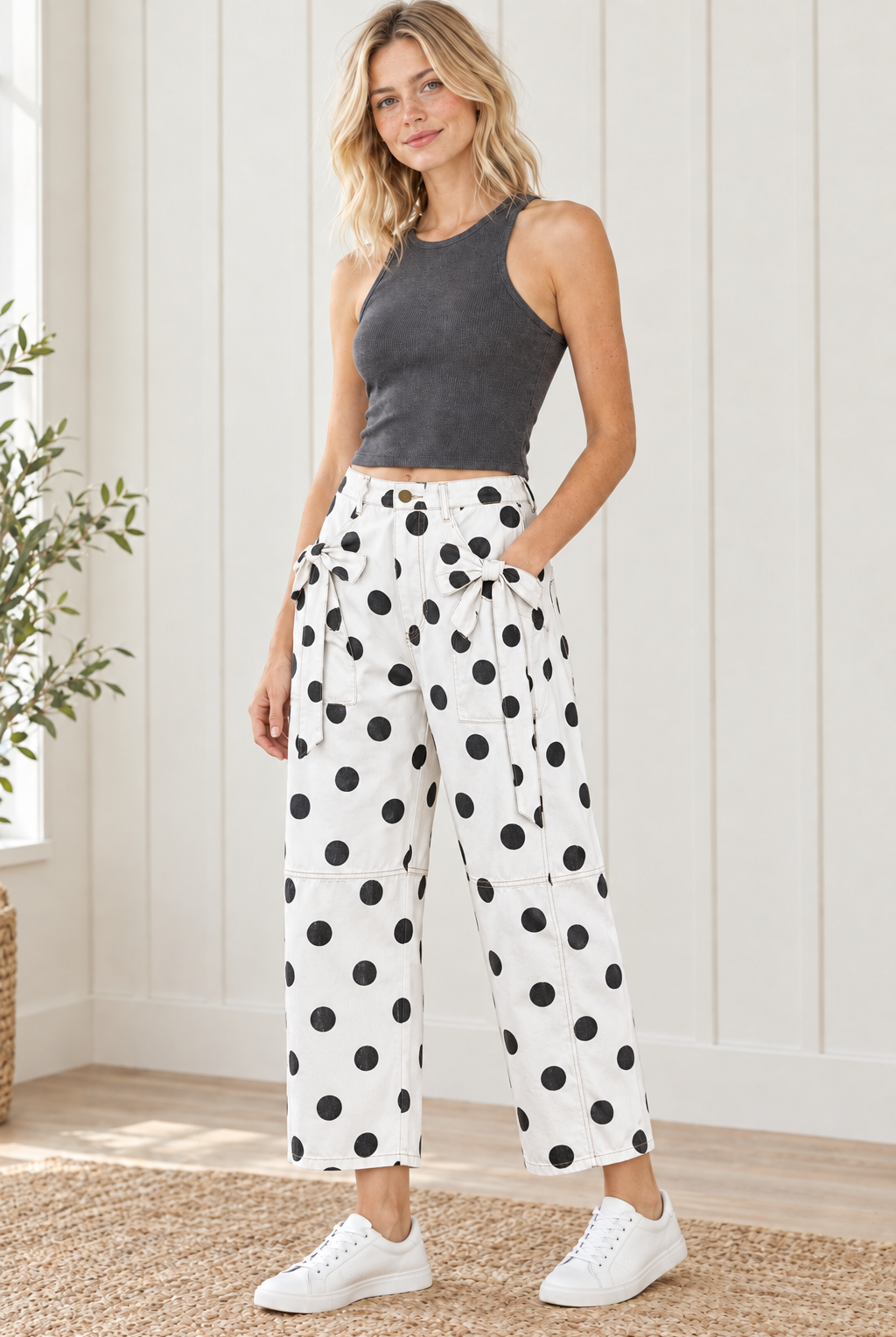 Angled view of white jeans with black polka dots, matching front pocket bows and relaxed ankle-length legs