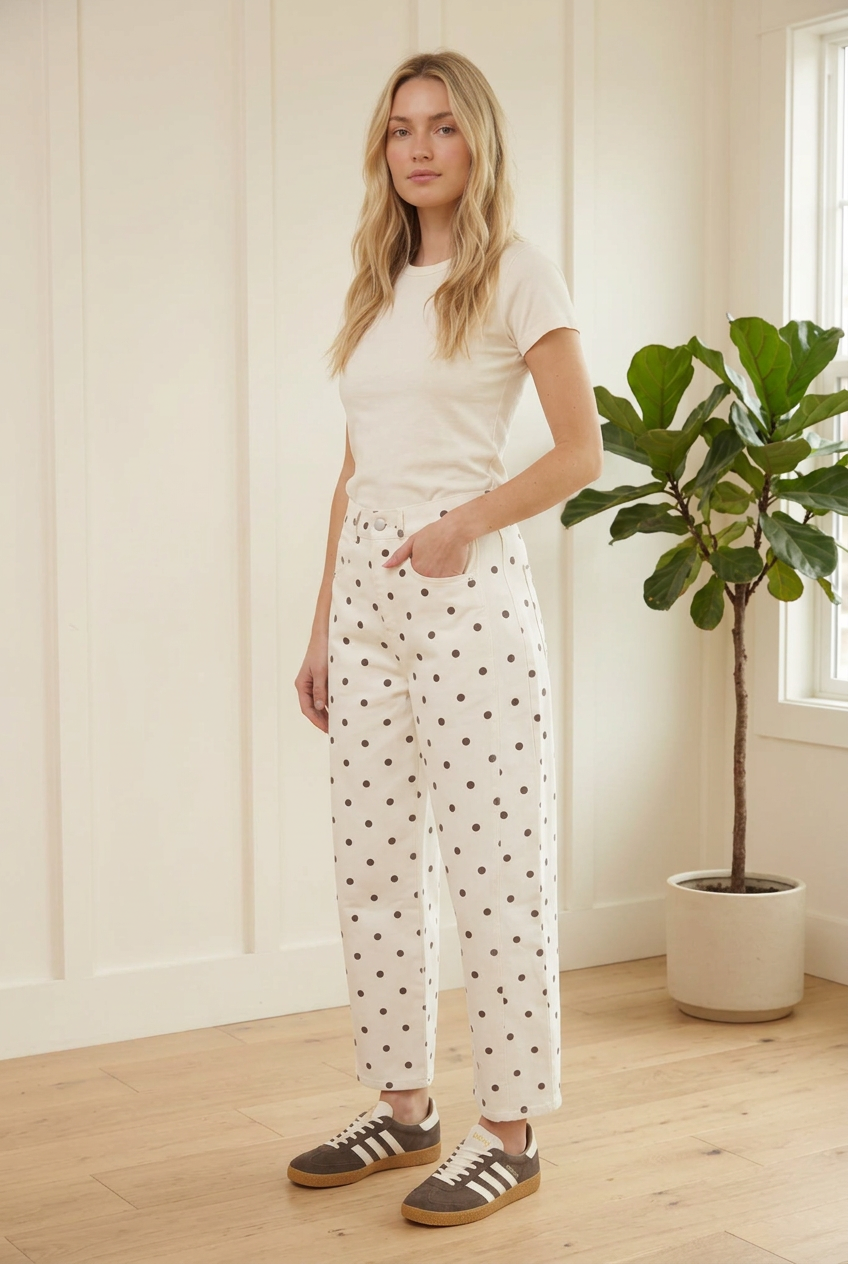 Side view of ecru barrel leg jeans with dark polka dots, curved side panels and cropped finished hems.