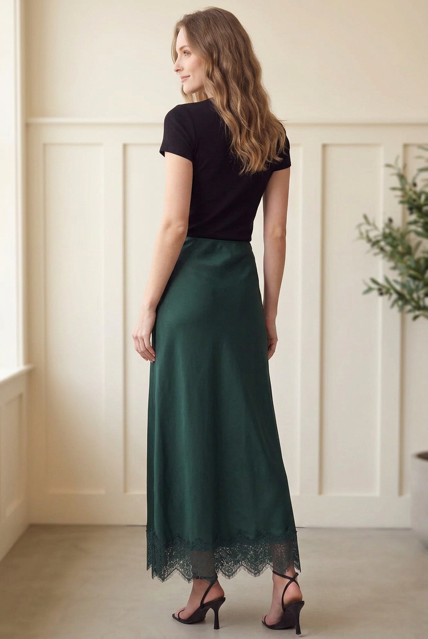 Back view of forest green woven satin maxi skirt with a flowing shape and scalloped lace hem.