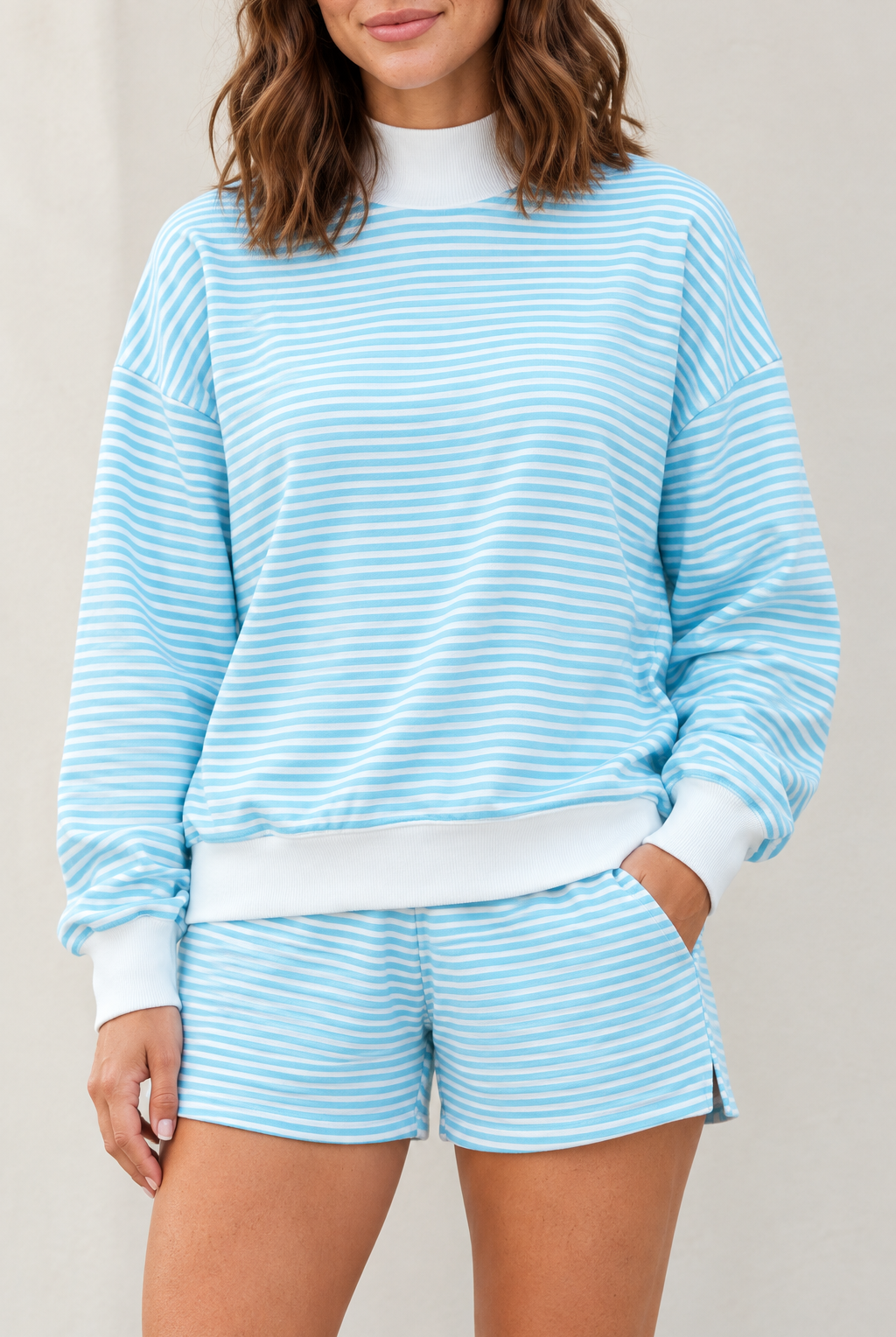 Close-up of sky blue lounge set showing fine horizontal stripes, white ribbed mock neck, cuffs and wide hem band