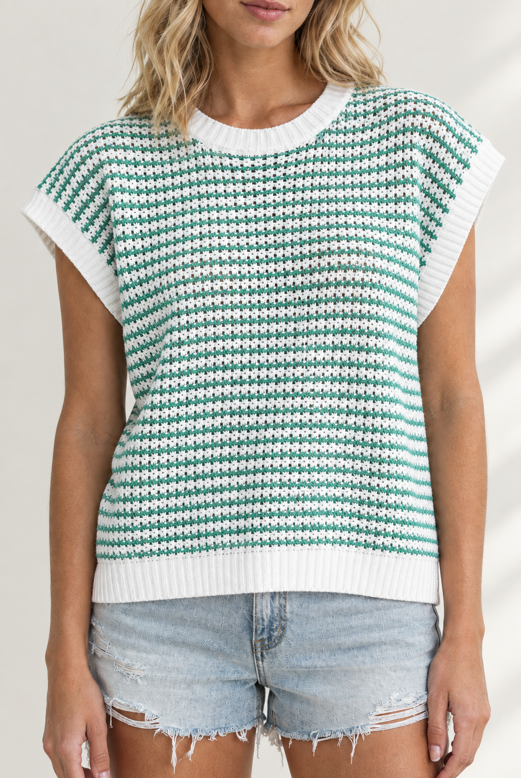 Close-up of green and white striped knit tank showing yarn texture and white ribbed neckline, armholes and hem
