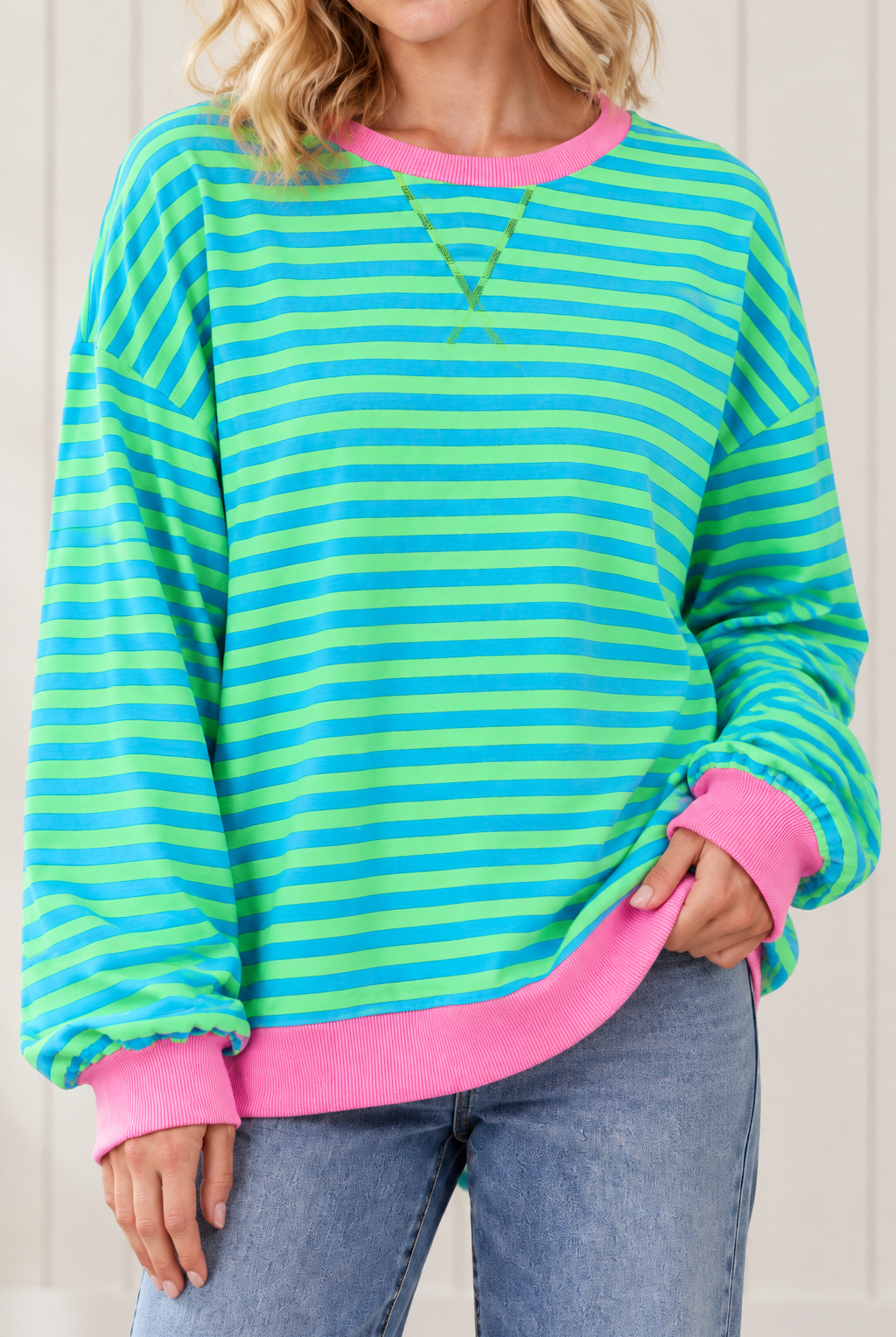 Close-up of blue and green striped pullover highlighting front V stitching, pink ribbed neckline and cuffs.
