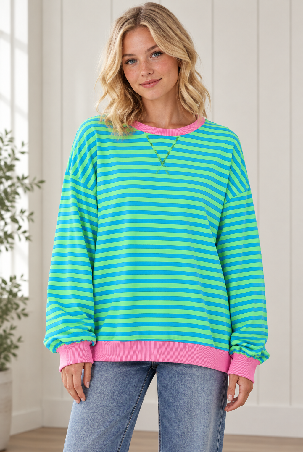 Front view of women's oversized blue and green striped pullover with pink crew neckline, cuffs and hem.