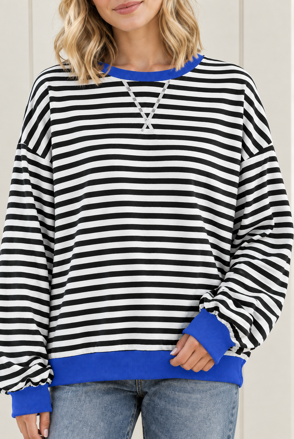 Close-up of striped sweatshirt with blue ribbed crew neckline, white V stitching and contrasting blue cuff.