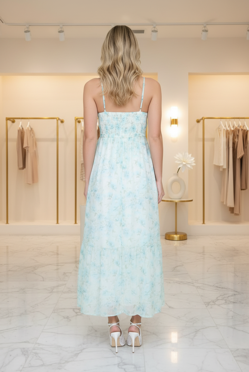 Back view of mint blue floral midi dress with adjustable spaghetti straps and smocked corset bodice, styled in a boutique setting