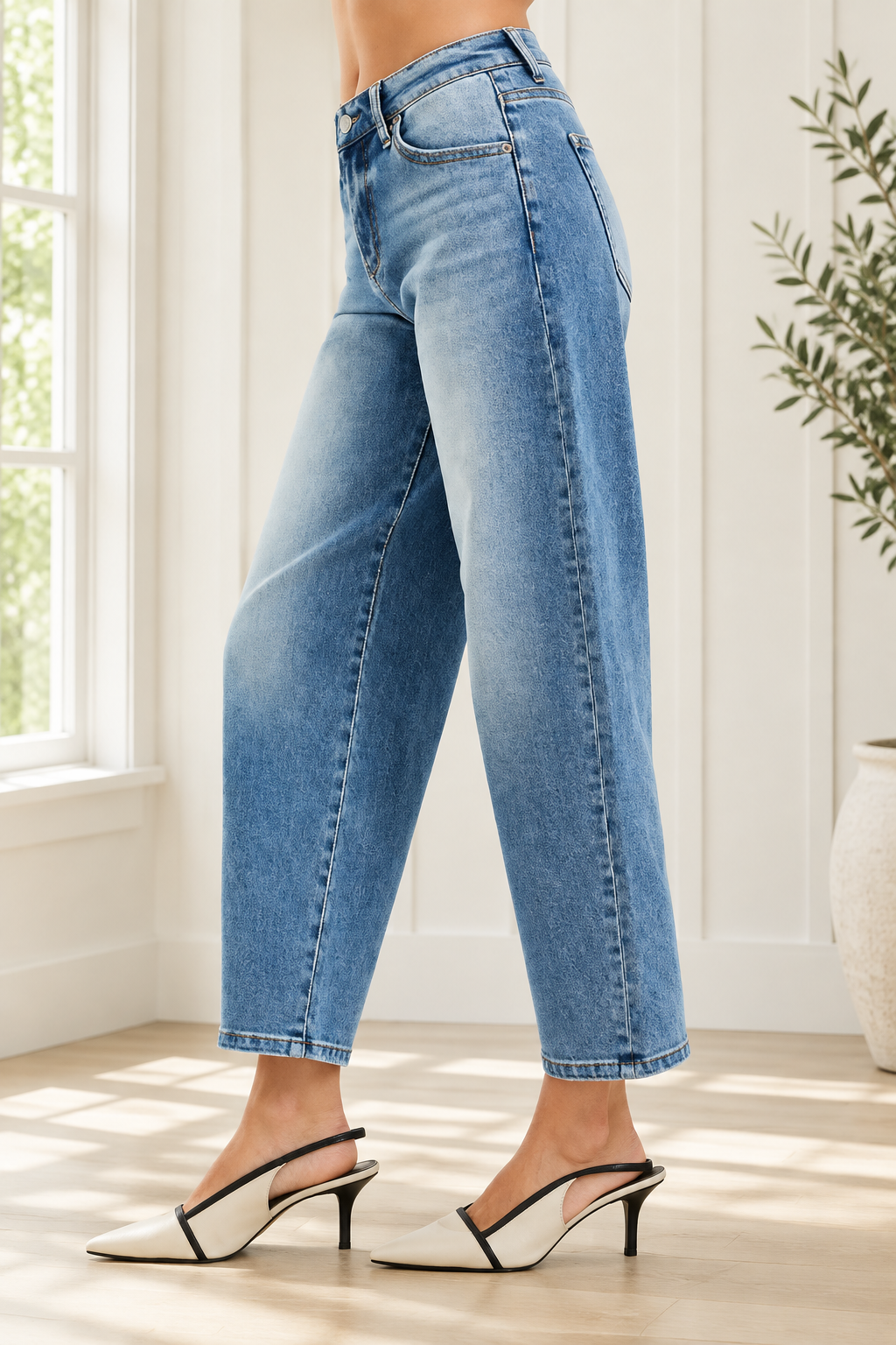 Side view of high rise barrel jeans showing the curved leg silhouette, side seam and tapered ankle opening